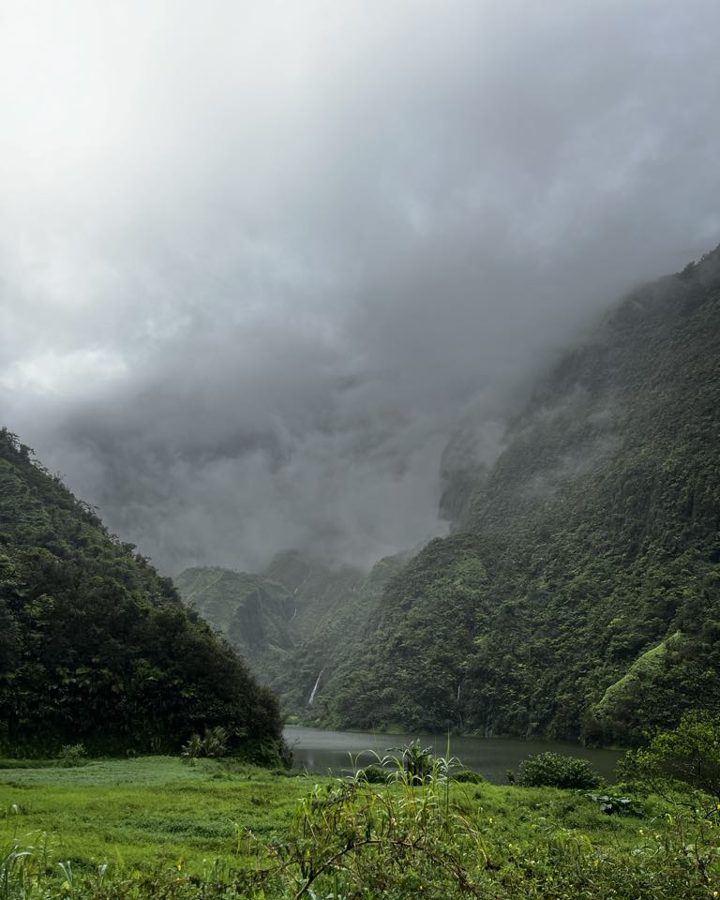A lush green valley under low, misty clouds.